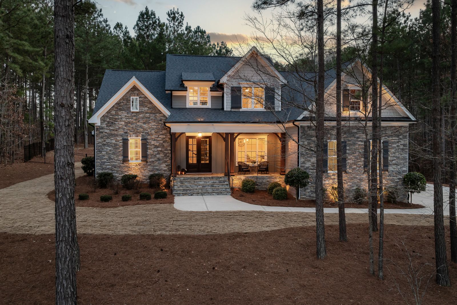 Stone-clad modern farmhouse at dusk with warm glowing windows representing the Northwest Side
