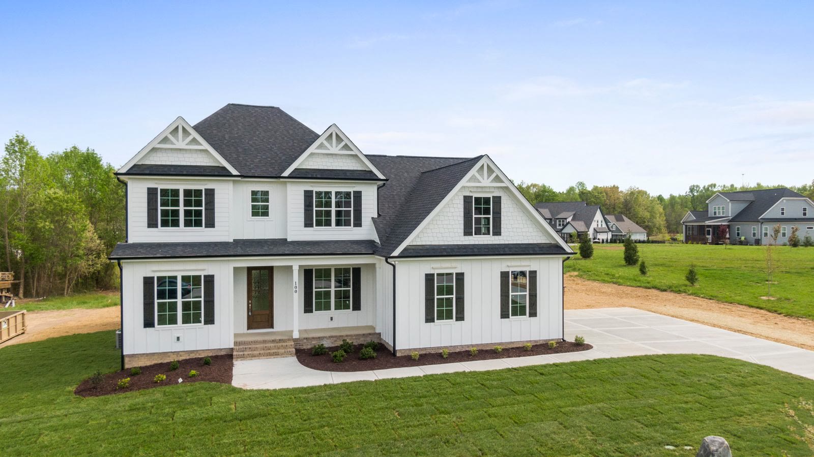 Two-story modern farmhouse with white board-and-batten siding, brick base, and charcoal roof